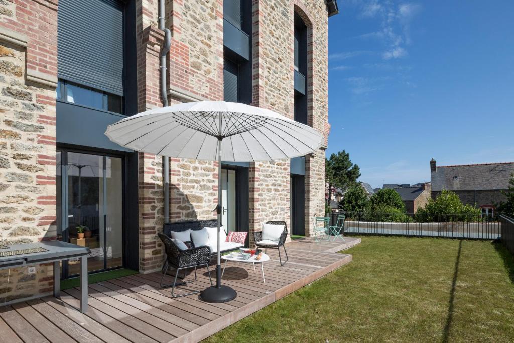 un patio con sombrilla, 2 sillas y una mesa en Le Ponant by Cocoonr, en Dinard