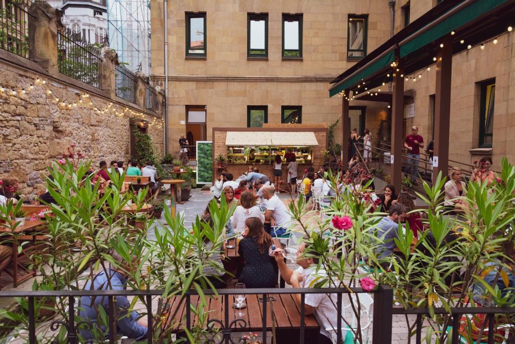 A Room In The City Hostel في سان سيباستيان: مجموعة من الناس يجلسون على الطاولات في المبنى