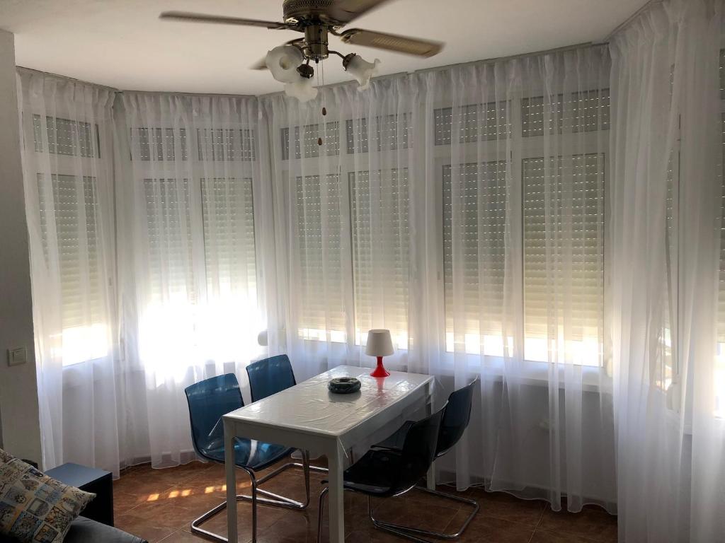 トレモリノスにあるArtas Apartamentosのダイニングルーム(白いカーテン、テーブル、椅子付)