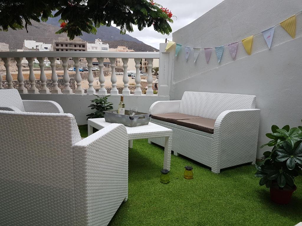 eine Terrasse mit weißen Korbstühlen und einem Tisch in der Unterkunft Apartamento Adeje II in Adeje