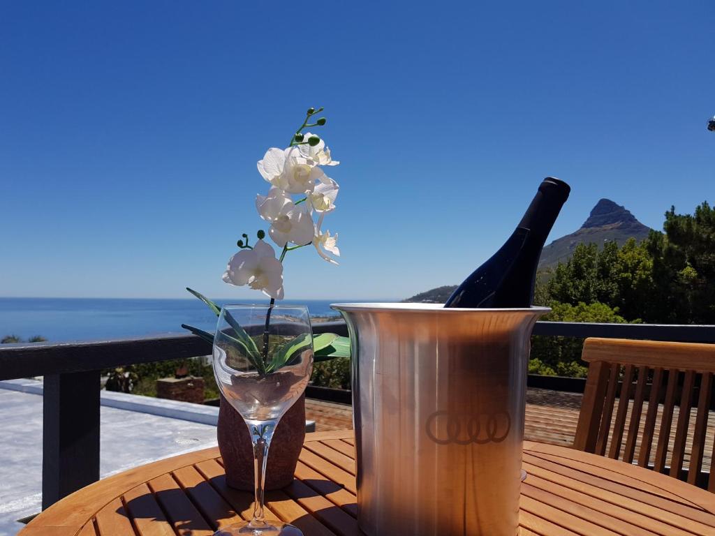 a wooden table with a vase and a bottle of wine at Camps Bay Cosy Accommodation in Cape Town