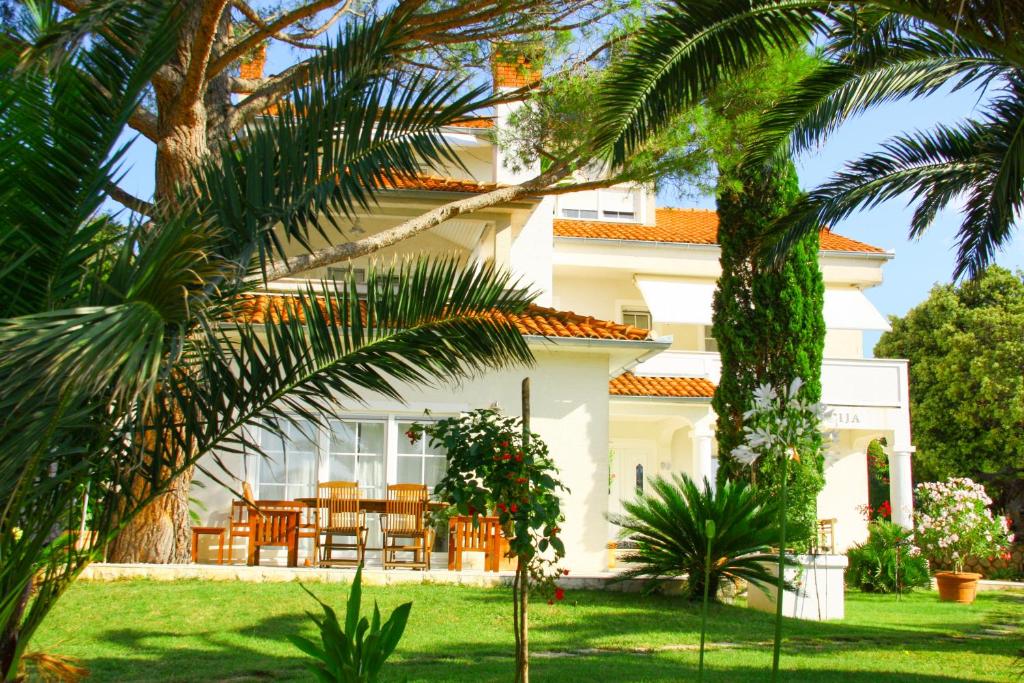 een wit huis met palmbomen ervoor bij Villa Lucija in Rab