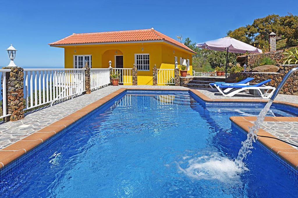 a swimming pool with a fountain in front of a house at Villa La Hoya in Tijarafe