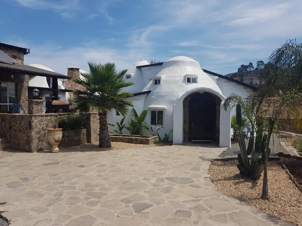 ein weißes Haus mit einer schwarzen Tür und einer Palme in der Unterkunft Hacienda Eco-Domes in Valle de Guadalupe