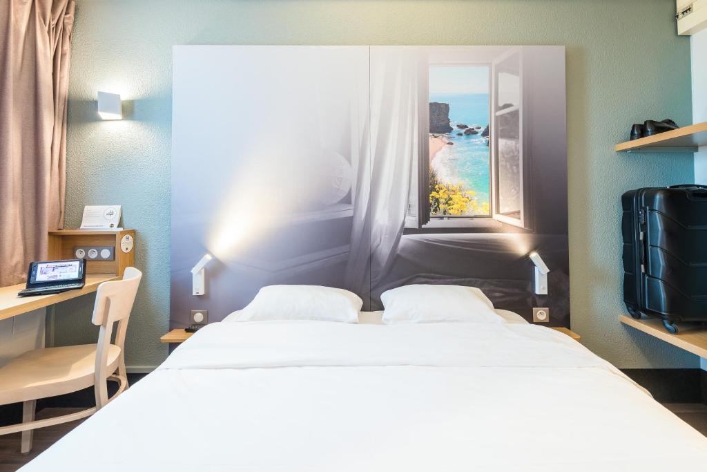 トリニャックにあるB&B HOTEL Saint-Nazaire Trignacのベッド2台と窓が備わるホテルルームです。