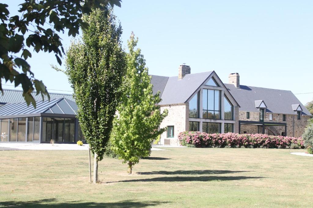 un arbre devant un grand bâtiment dans l'établissement Domaine du Jardin " Chambres d'hôtes ", à Saint-Jean-de-la-Haize