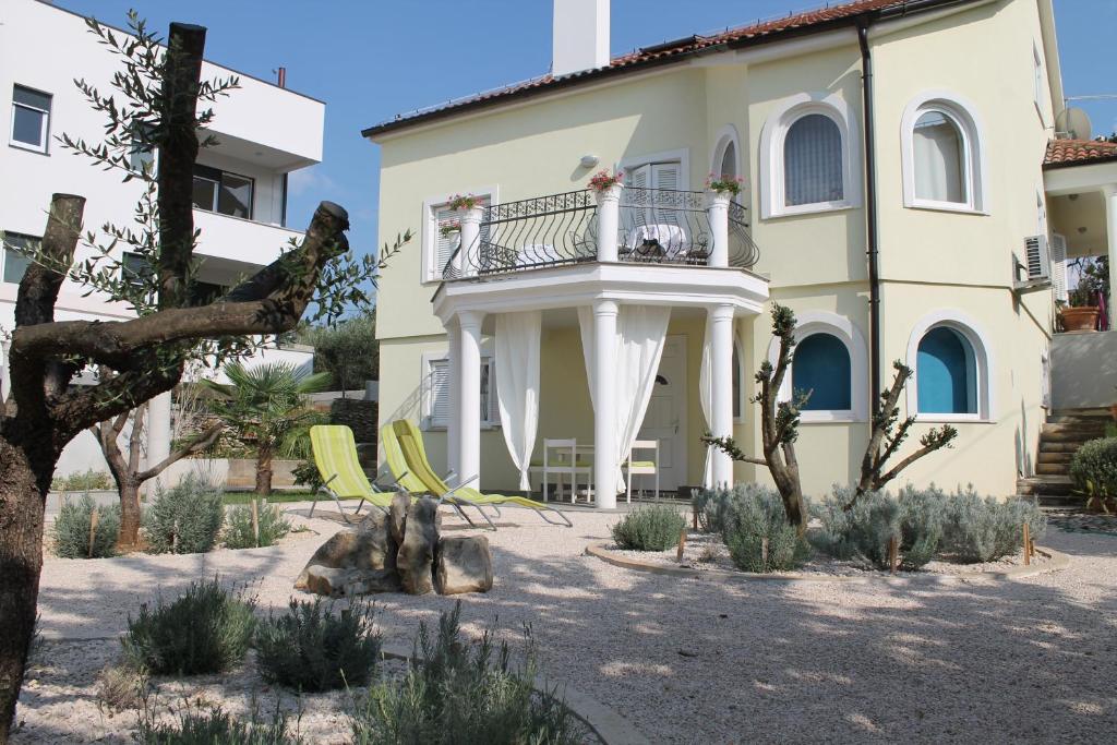 a house with a balcony and chairs in a yard at Villa Mandolina Apartments in Zadar
