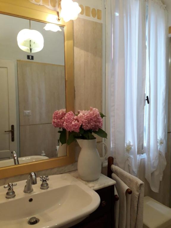 W łazience znajduje się umywalka i waza z różowymi kwiatami. w obiekcie Tenuta Crescentini-ValleMura ,appartamenti con entrata indipendente w mieście San Donà di Piave