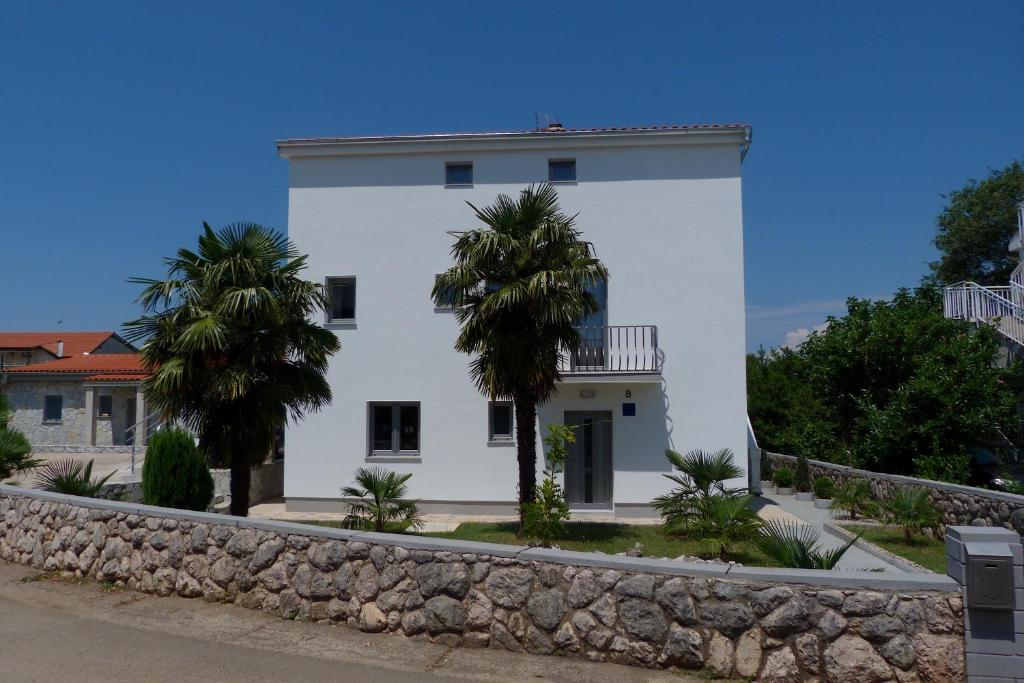 a white house with two palm trees in front of it at Apartments Monja & Dadi in Vantačići