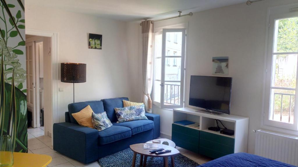 sala de estar con sofá azul y TV en Le Studio 54 en Honfleur