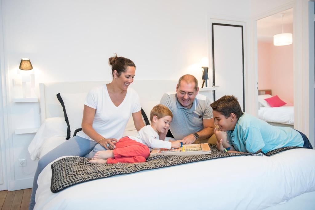 a family sitting on a bed reading a book at Au Coeur De Beauvais in Beauvais