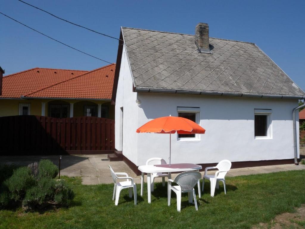 - une table et des chaises avec un parasol orange dans la cour dans l'établissement Apartment Balatonbereny 9, à Balatonberény