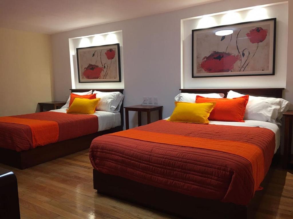 Zimmer mit 2 Betten mit orangefarbenen und gelben Kissen in der Unterkunft Hotel Santa Lucia del Bosque in San Luis Potosí