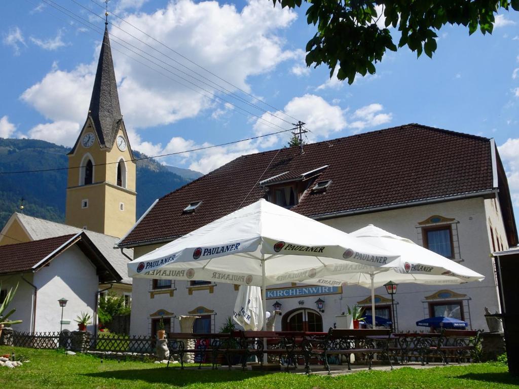 una iglesia con un paraguas blanco delante de un edificio en Kirchenwirt Kolbnitz en Unterkolbnitz