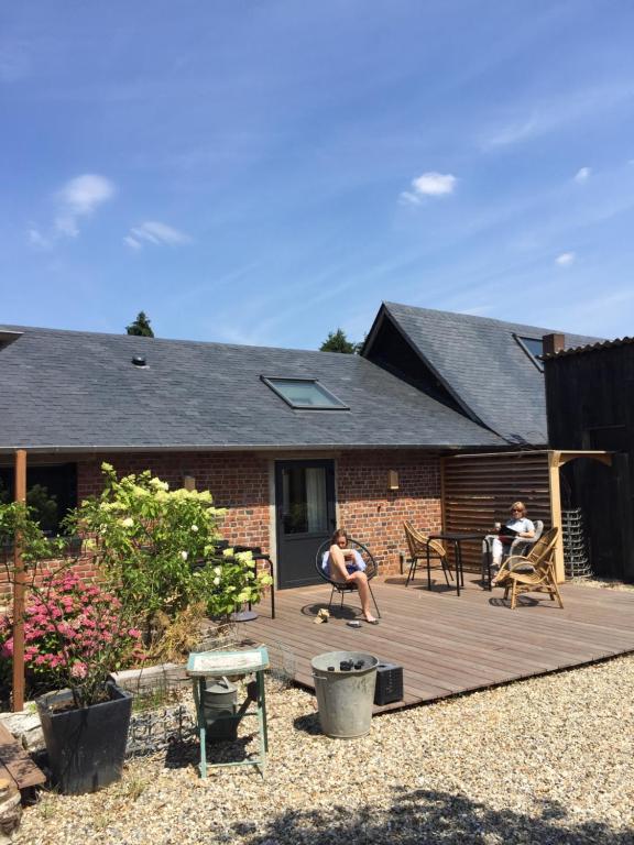 two people sitting on a deck in front of a house at L’abri du monde in Fleury-la-Forêt