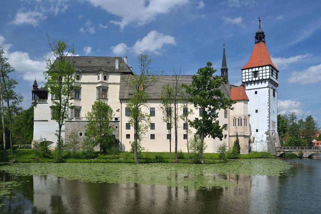 ein großes weißes Schloss mit einem Uhrturm neben einem See in der Unterkunft CASTLE AREA BLATNÁ in Blatná