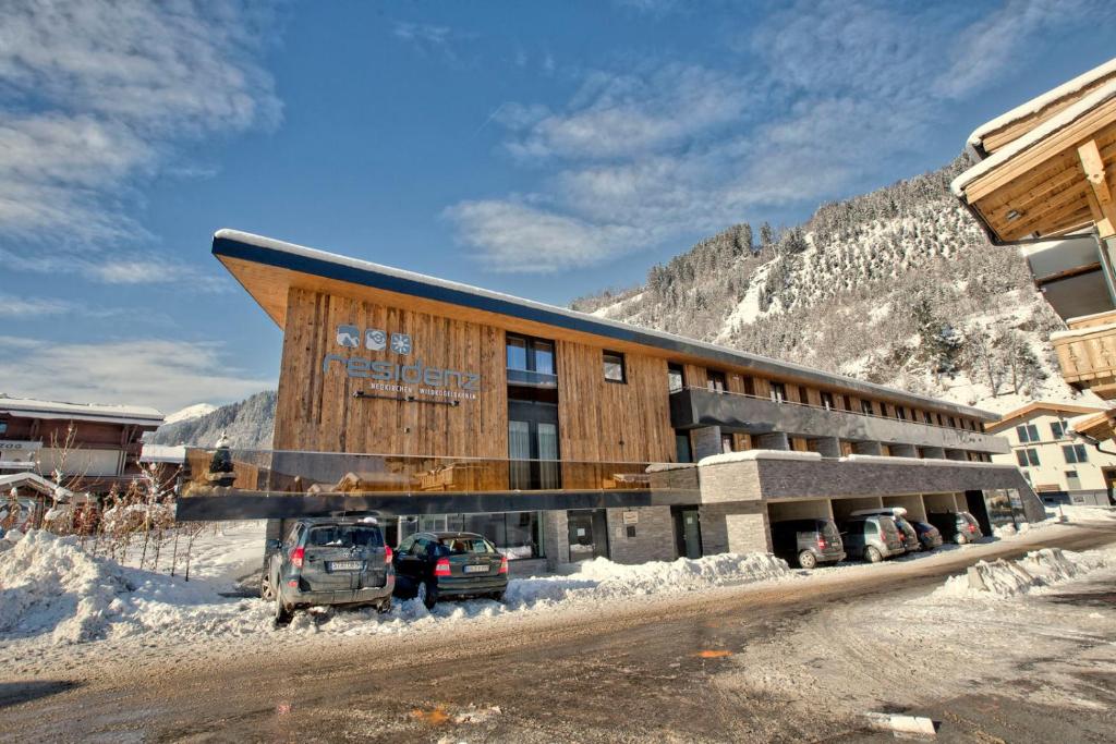 ein großes Gebäude mit einem davor geparkt in der Unterkunft Residenz Wildkogelbahnen Top 10 in Neukirchen am Großvenediger