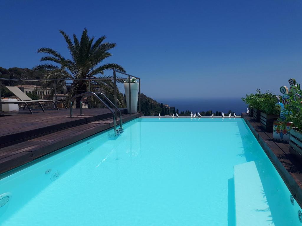 a large blue swimming pool with a view of the ocean at Il Piccolo Giardino GH ***Superior in Taormina