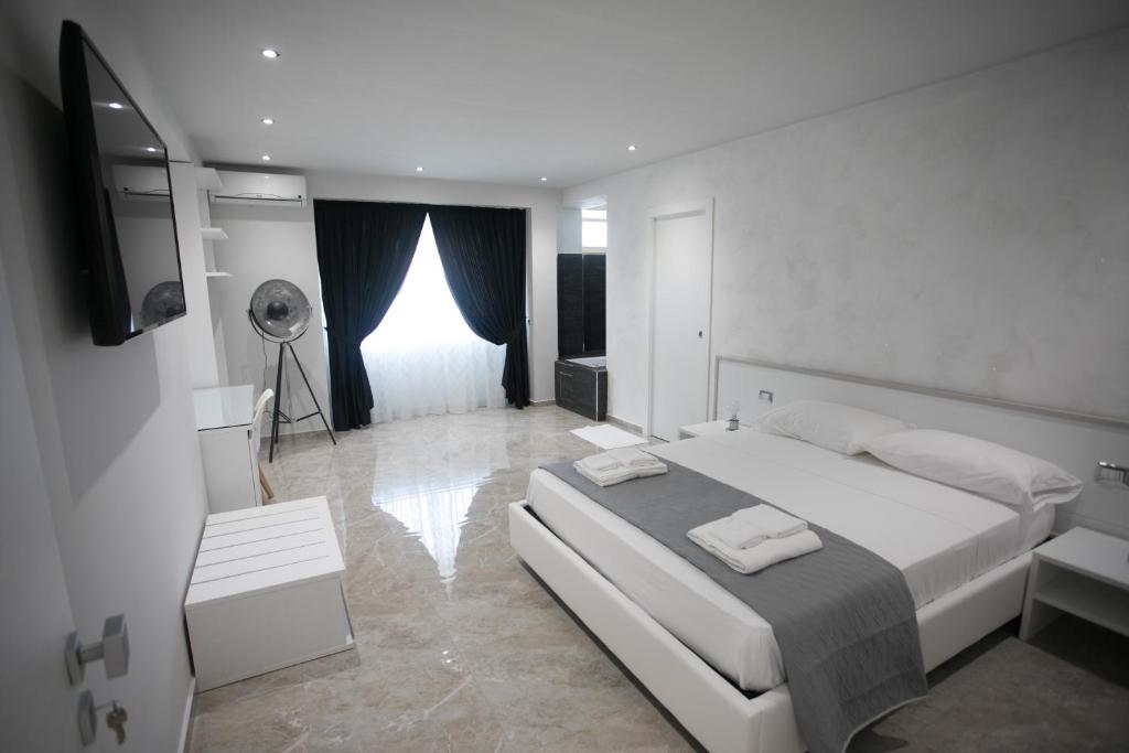 a white bedroom with a large bed and a television at Tropea Luxury & Charm in Tropea