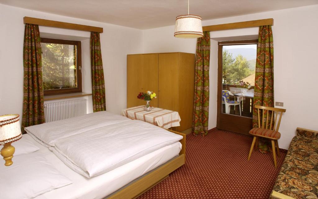 1 dormitorio con 1 cama, 1 silla y 1 ventana en Muller Private Rooms, en Ortisei