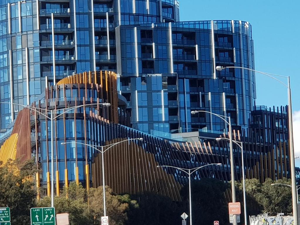 un edificio de cristal alto con un letrero de la calle delante de él en Ivanhoe Apartments, en Melbourne