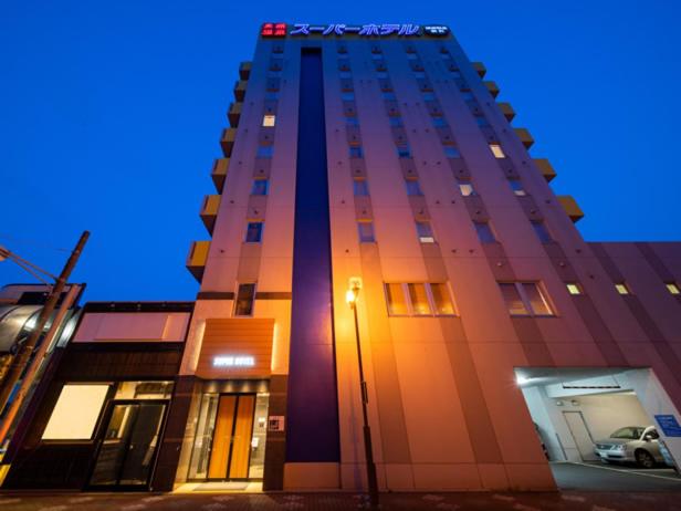 un edificio alto con una luz de la calle delante de él en Super Hotel Towada Natural Hot Springs en Towada