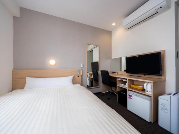 una camera d'albergo con letto e TV di Super Hotel Hachinohe Nagayokocho a Hachinohe