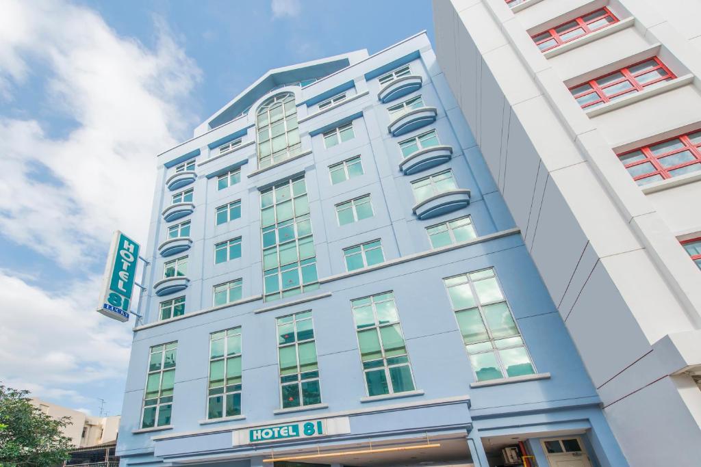 um edifício branco alto com um cartaz em Hotel 81 Lucky em Singapura