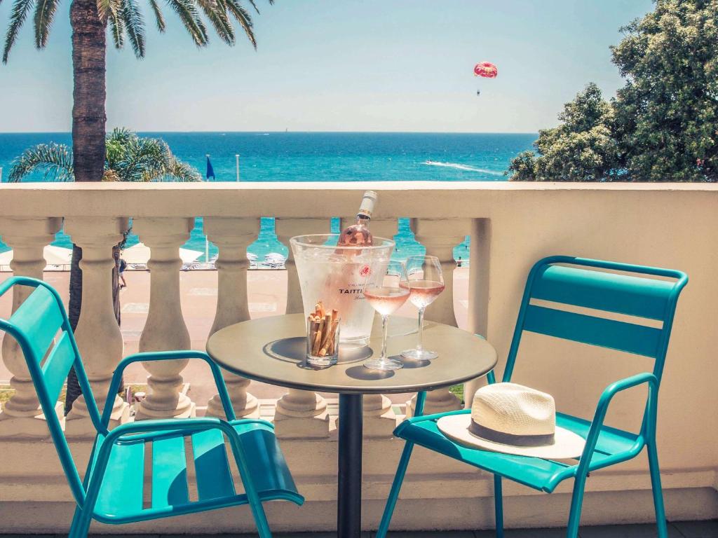 a table with two chairs and wine glasses on a balcony at Mercure Nice Marché Aux Fleurs in Nice