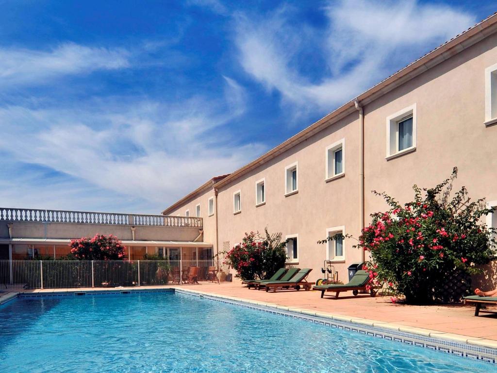 a building with a swimming pool in front of a building at ibis Orange Sud in Orange