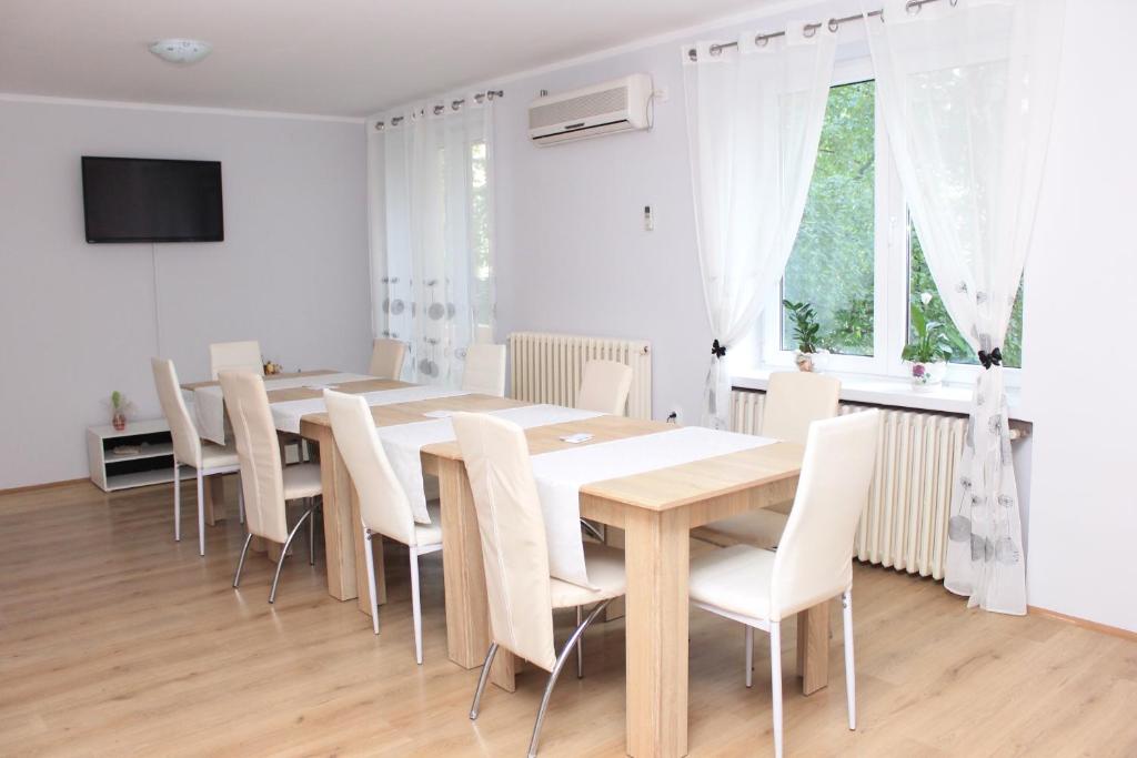 a dining room with a wooden table and white chairs at A&A in Novi Sad