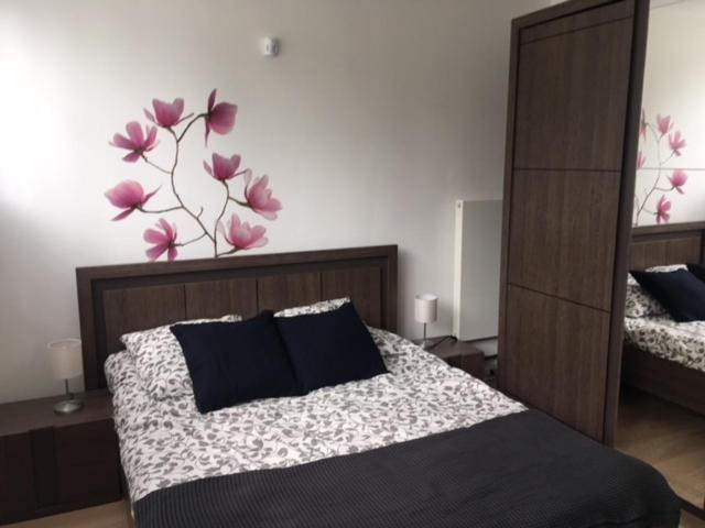 1 dormitorio con 1 cama con flores púrpuras en la pared en T2 proche PARIS et gare TGV MASSY, en Massy