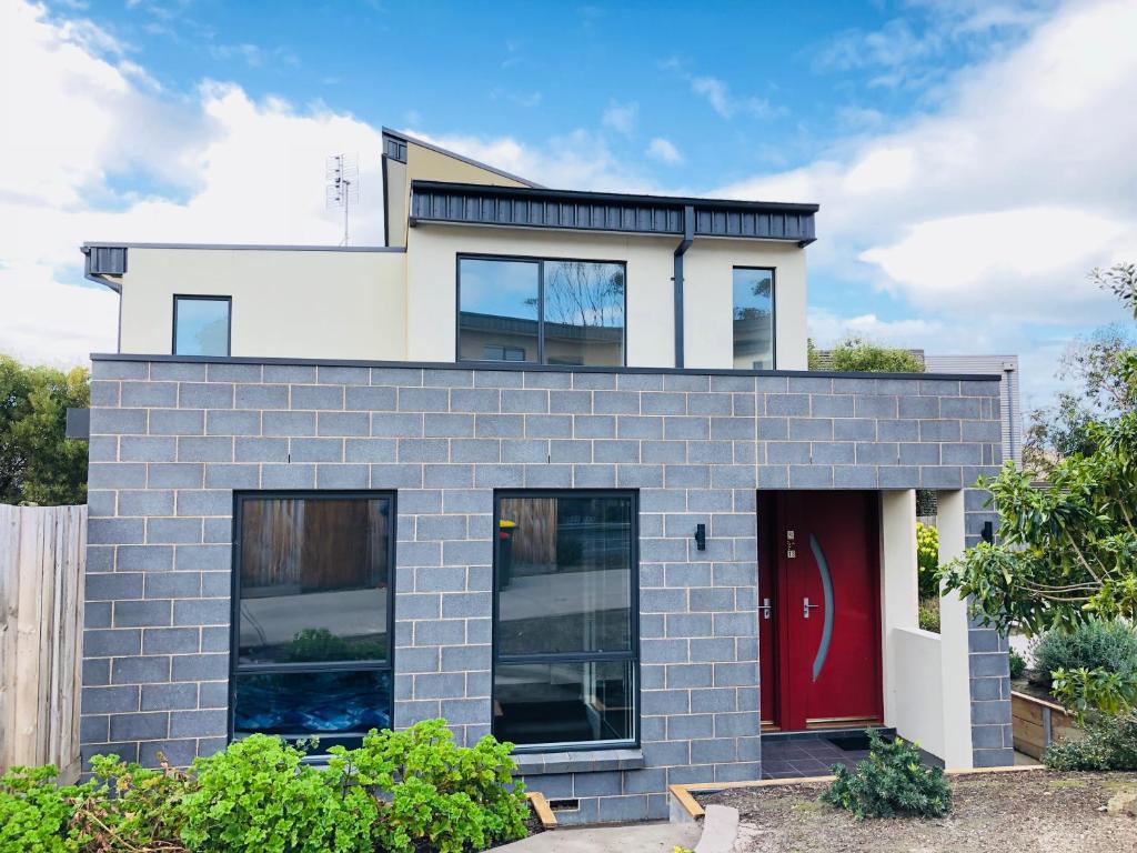 a blue brick house with a red door at Apollo Bay Seal Apartments in Apollo Bay