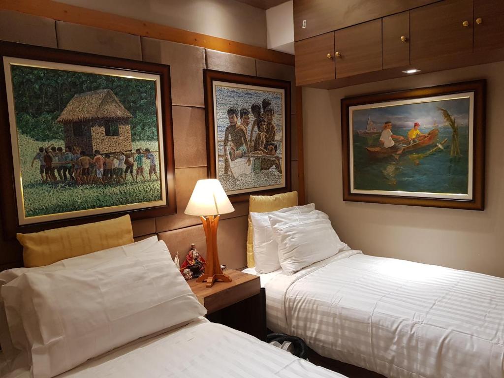 um quarto de hotel com duas camas e um quadro na parede em Stay Amare Residences Malate em Manila