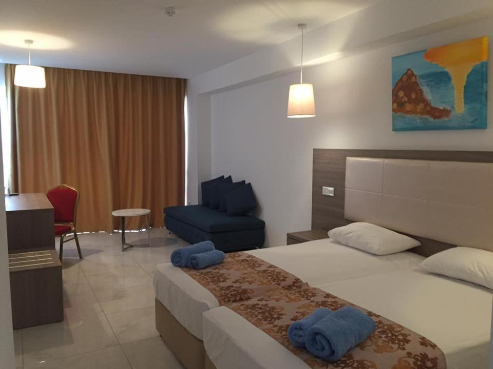 a hotel room with a bed and a blue chair at Corfu Hotel in Ayia Napa
