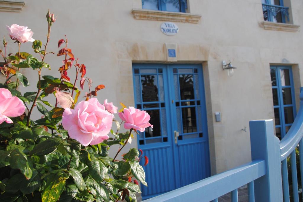 a blue door with pink roses in front of a building at Villa Madeleine in Arromanches-les-Bains