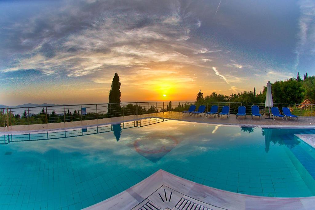 a pool with chairs and a sunset in the background at Studios Vrionis Panoramic Sunset in Kothréas