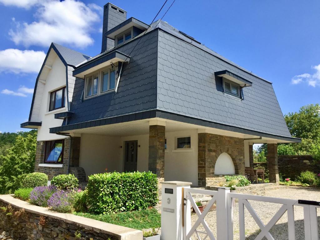 a house with a black roof and a white fence at La villa des Savoyards in Vielsalm