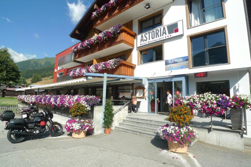 una motocicleta estacionada frente a un edificio con flores en Hotel Astoria, en Ulrichen
