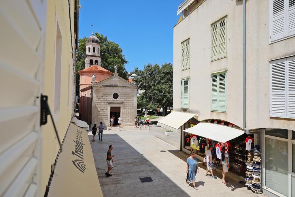 un grupo de personas caminando por una calle con una iglesia en Greta Residence, en Zadar