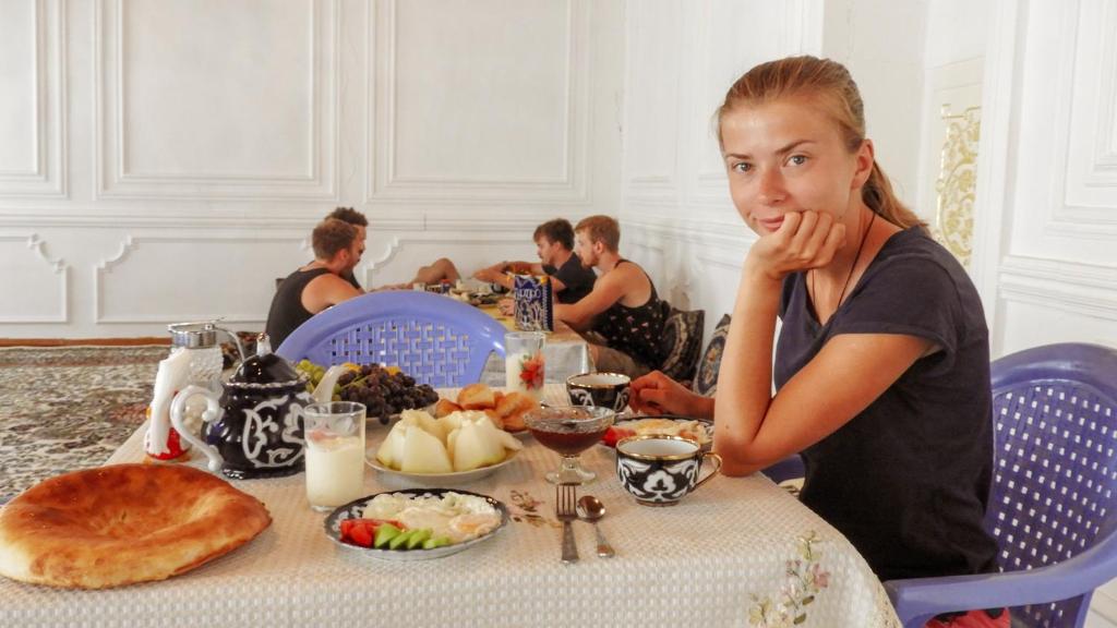 a woman sitting at a table with a plate of food at Diyor Hostel in Bukhara