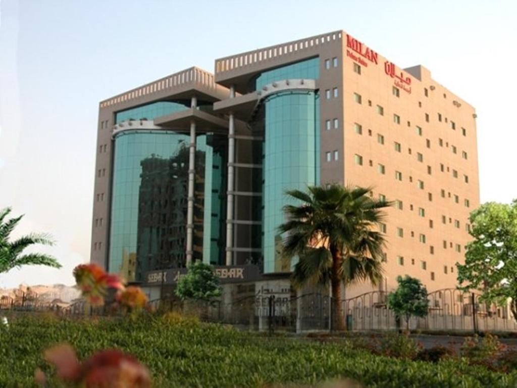 a large building with a palm tree in front of it at Milan Deluxe Suites in Al Khobar