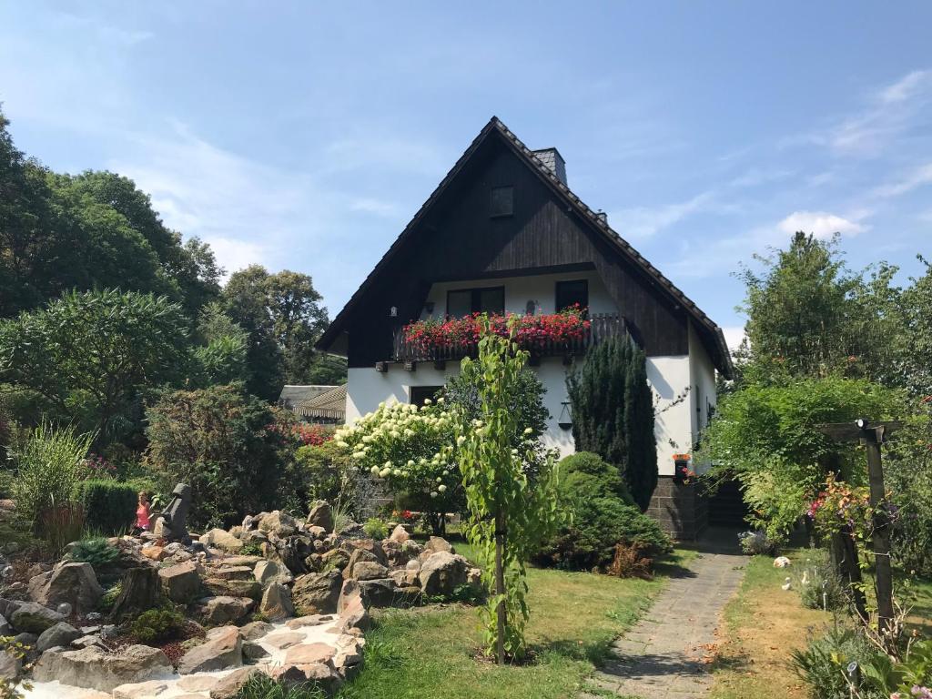 ein weißes Haus mit einem schwarzen Dach und einem Garten in der Unterkunft Ferienwohnung Familie Petschel in Kurort Jonsdorf