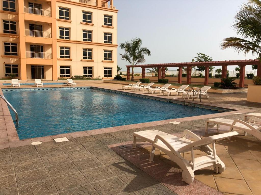 a swimming pool with lounge chairs and a building at Studio Marina 2 in King Abdullah Economic City