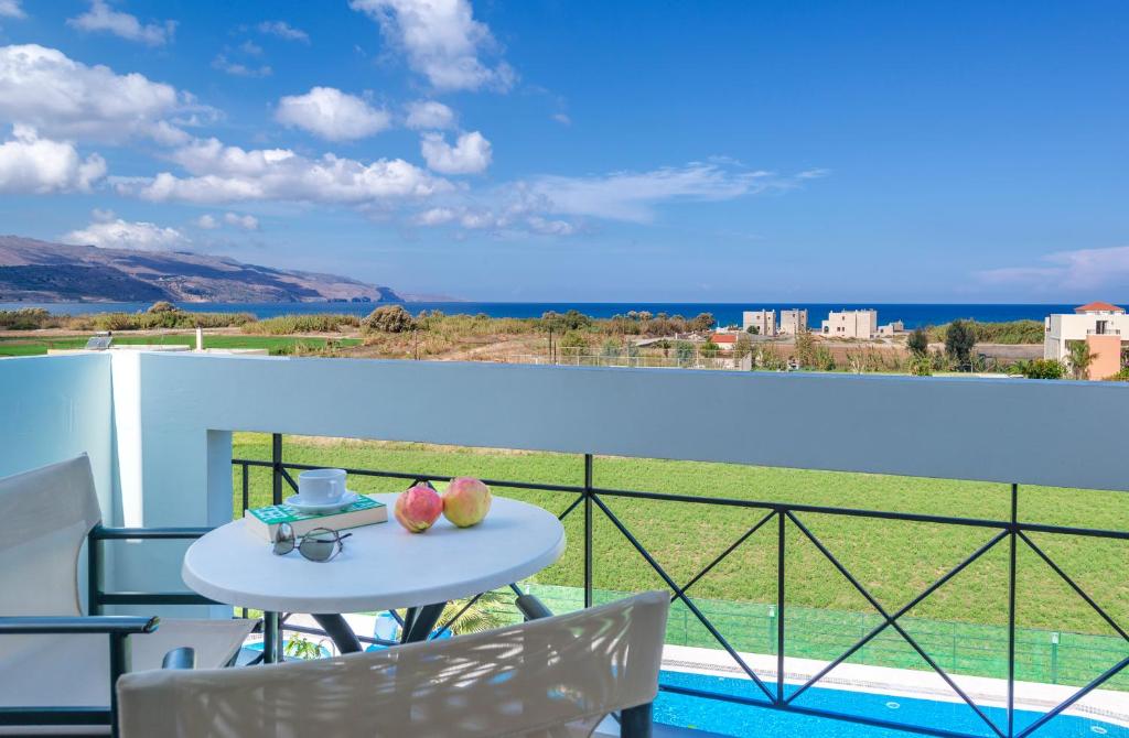 a table on a balcony with a view of the ocean at Selini Suites & Waterpark in Kolymvari