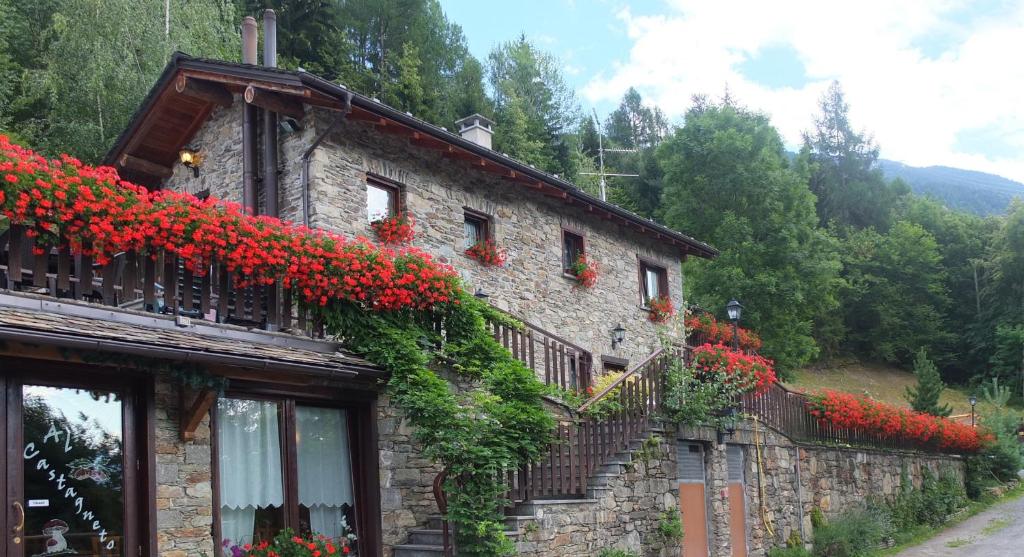 un edificio con flores rojas a un lado. en Agriturismo Al Castagneto, en Mazzo di Valtellina