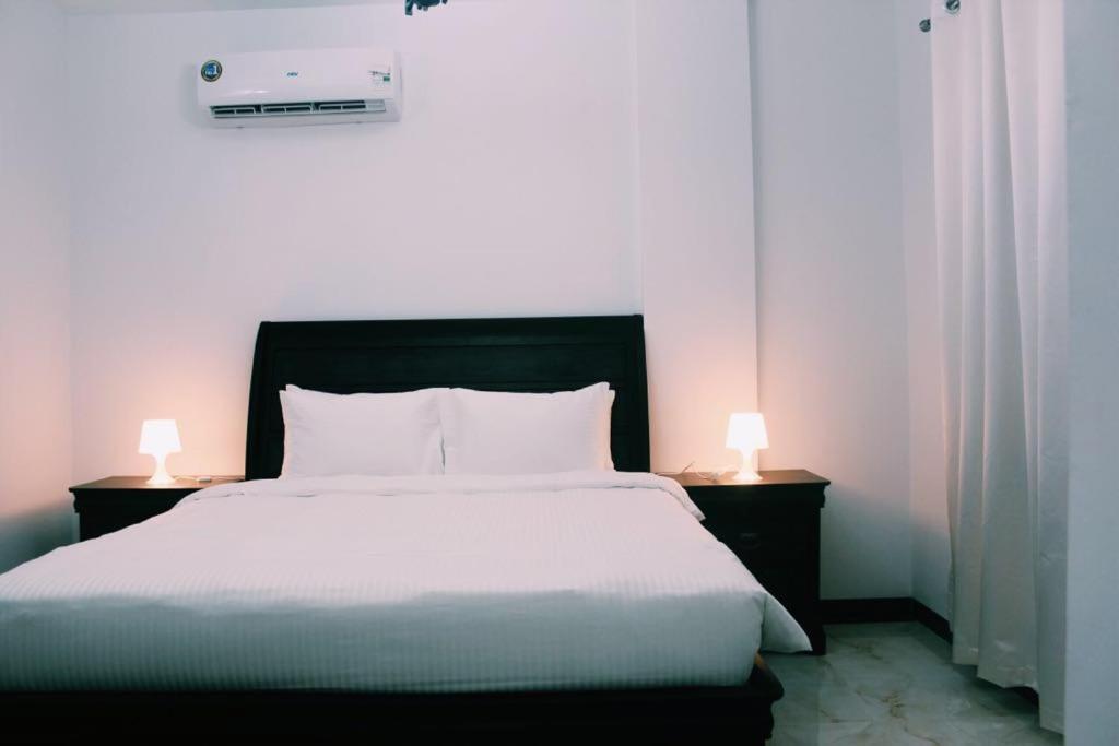 a bedroom with a large bed with two lamps on tables at Alhama Hotel Appartment in Mūkhī