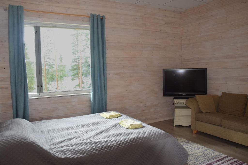 - une chambre avec un lit, une télévision et un canapé dans l'établissement Saimaa Hirsilinna Anttola, à Anttola