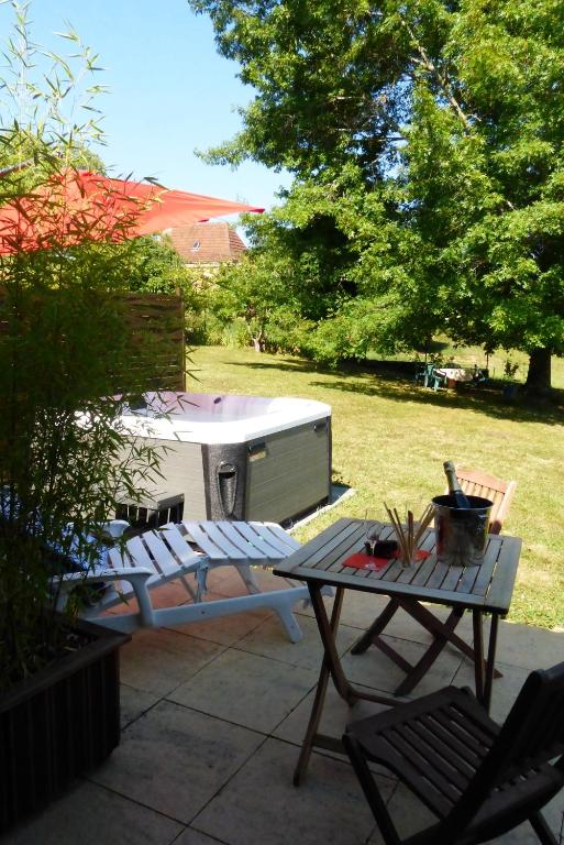 einen Hinterhof mit einem Grill sowie einem Tisch und Stühlen in der Unterkunft L'orée du bois in Frayssinet-le-Gélat