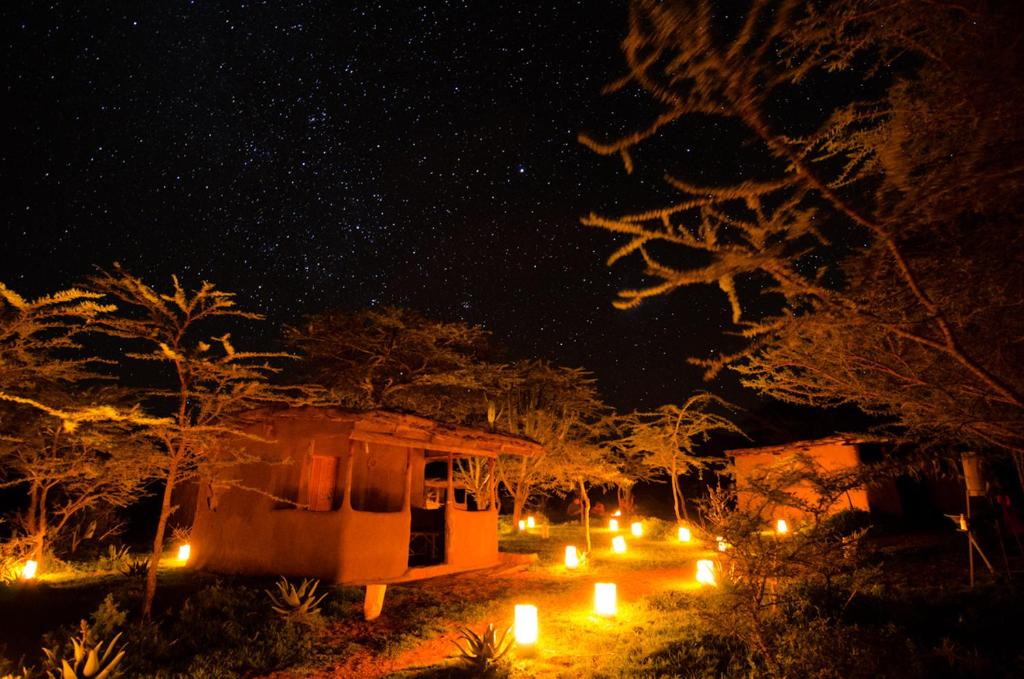 Una vista nocturna de una casa con velas delante en Maji Moto Maasai Cultural Camp en Narok